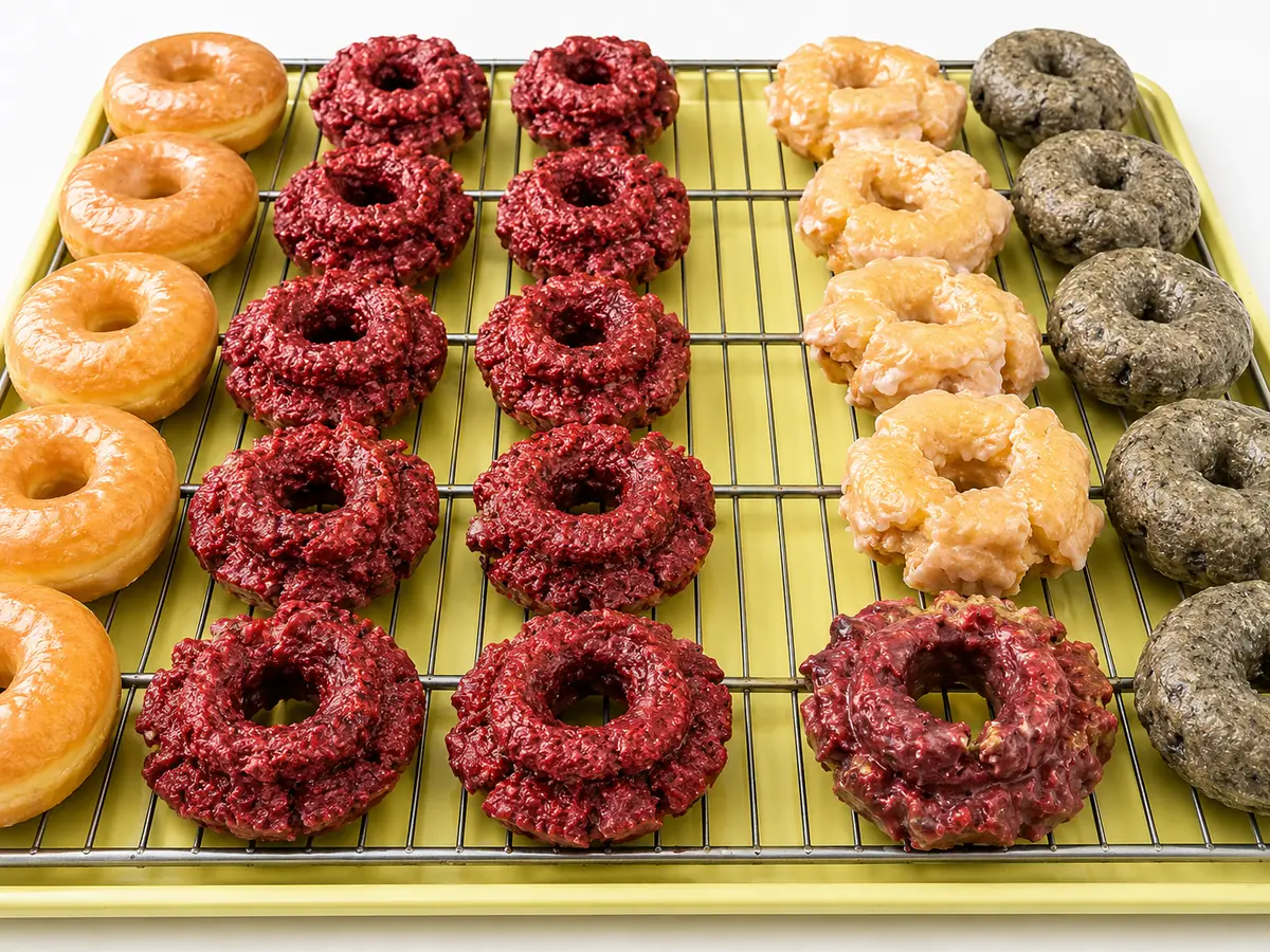 Rows of glazed, red velvet, crumbled, and powdered cake donuts on a gold tray at Atlanta Donuts.