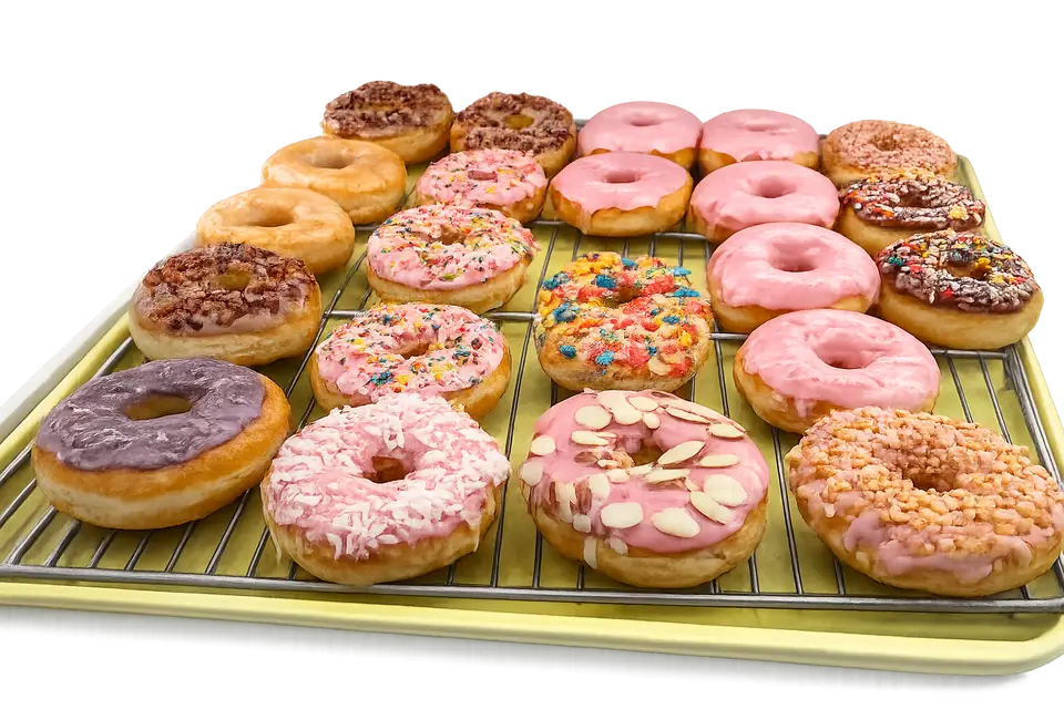 Pink, chocolate, and white-frosted donuts with colorful toppings on a rack at Atlanta Donuts.
